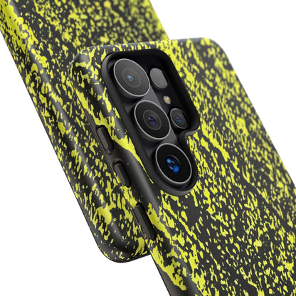 A close-up of a smartphone case with a black and neon yellow splatter pattern, fitted on a phone with a triple-camera system, shown against a plain white background.