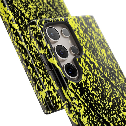 A close-up of a smartphone case with a black and neon yellow splatter pattern, shown fitted on a phone against a clean white background.