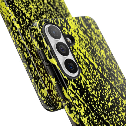 A close-up of a smartphone case with a black and neon yellow splatter pattern, shown on a phone against a plain white background.