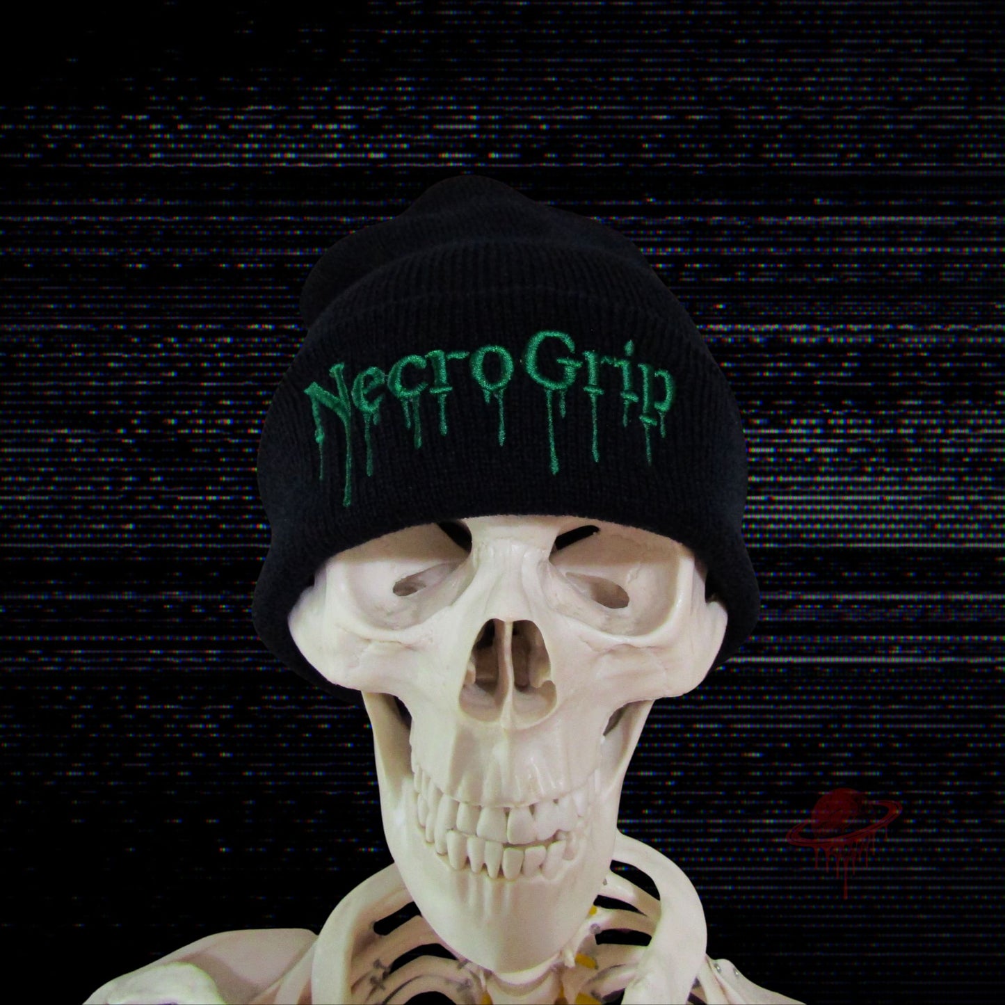 Skeleton model wearing black cuffed beanie embroidered with NecroGrip drip logo in toxic green, glitch-distorted background.